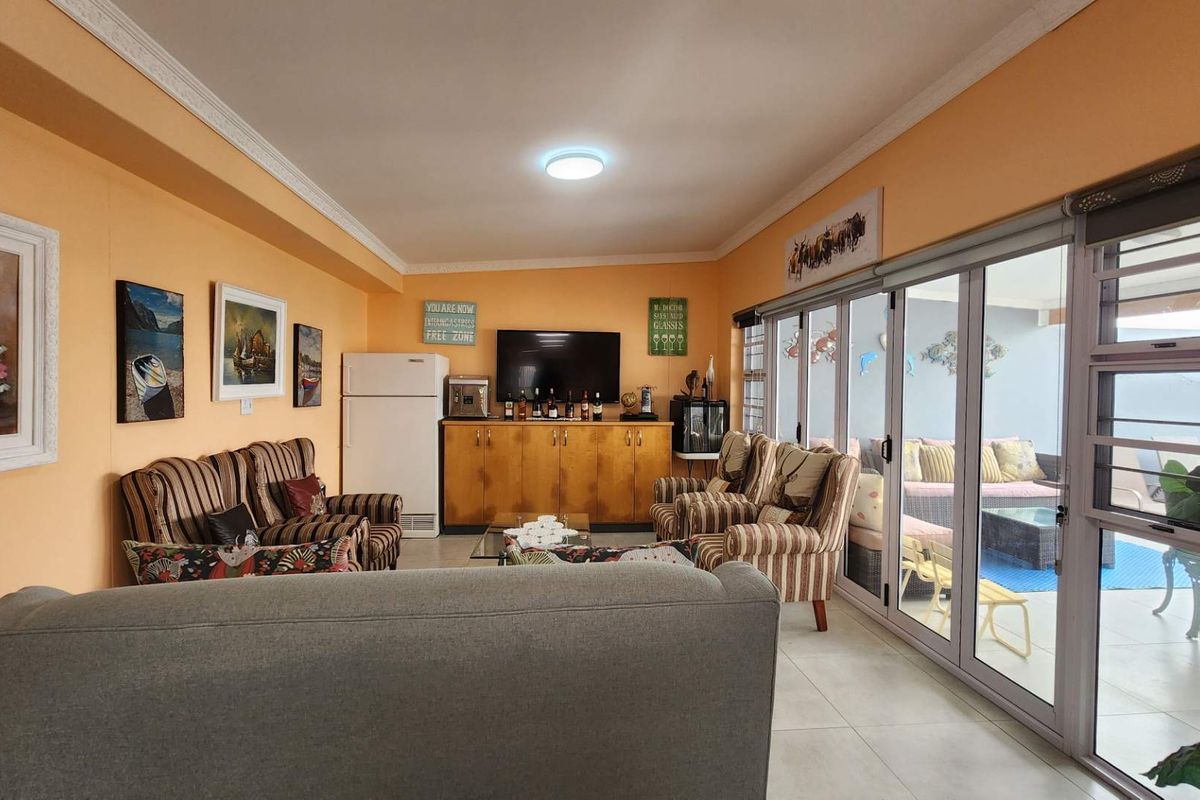 Spacious living room featuring tiled flooring, crown molding, and large sliding glass doors that provide seamless access to the outdoor patio area.