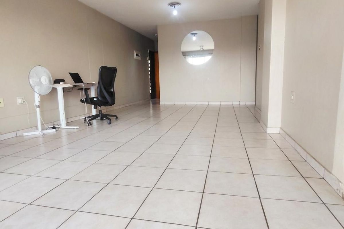 A spacious, open-plan living area featuring neutral wall tones and ceramic floor tiles, highlighted by a unique circular architectural cutout.