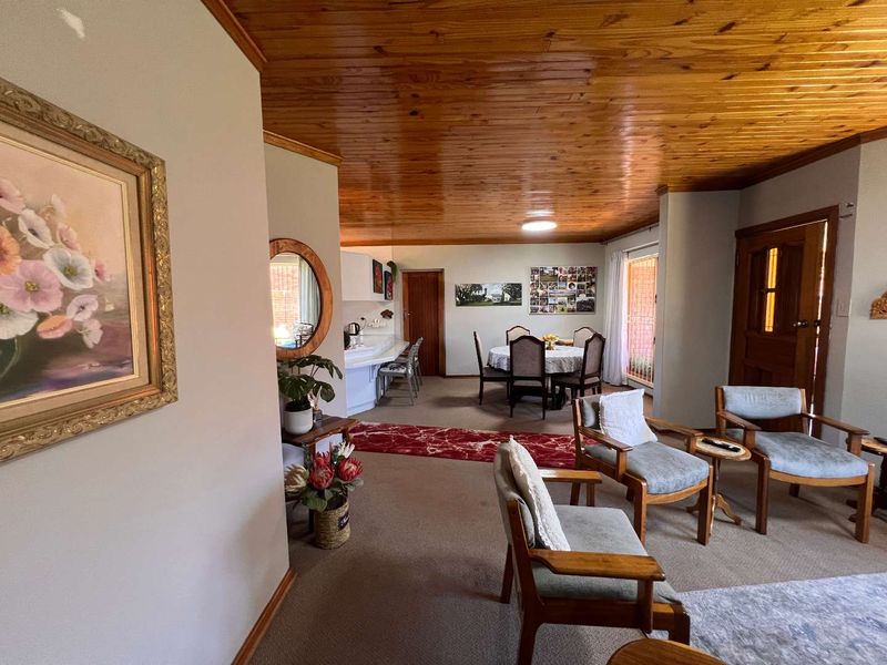 Open plan living and dining area featuring a distinctive timber tongue and groove ceiling and neutral wall finishes.