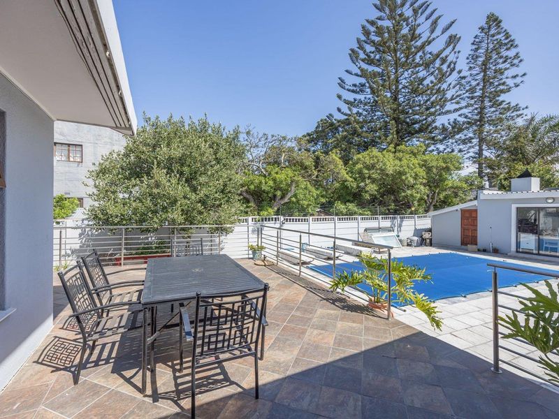Spacious outdoor patio area featuring tiled flooring, stainless steel balustrades, and direct access to a swimming pool with a cover.