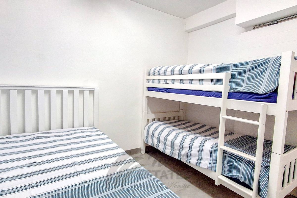 A functional bedroom space featuring neutral walls and tiled flooring, suitable for multiple occupants.