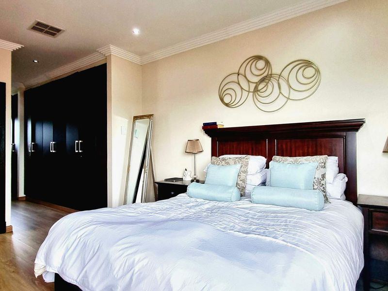 A well-maintained bedroom featuring dark built-in cupboards, laminate flooring, and decorative cornicing, providing a clean and functional living space.