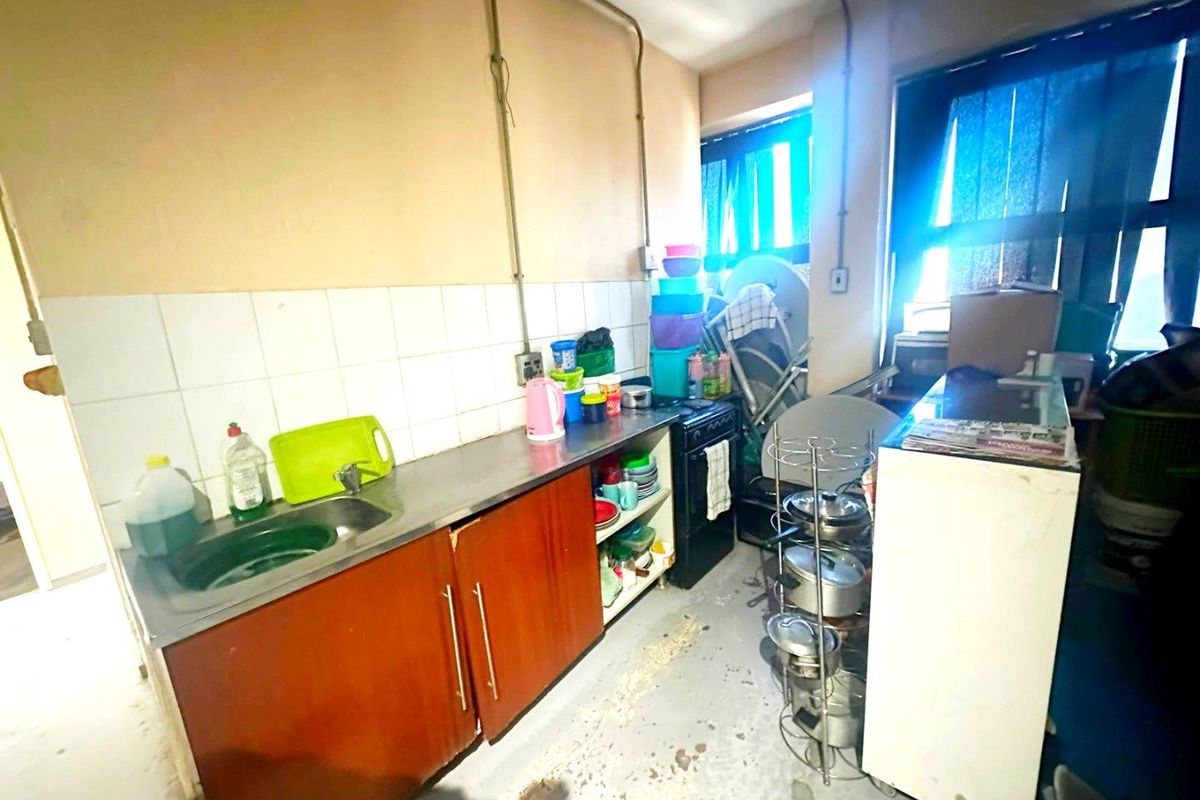 A functional kitchen area featuring a stainless steel sink, tiled splashback, and basic cabinetry, requiring cosmetic updates to improve its overall condition and appeal.
