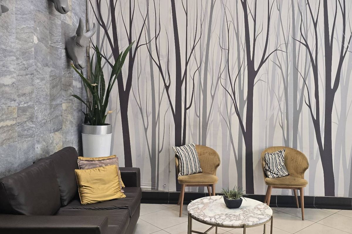 A living area featuring decorative stone wall cladding and patterned wallpaper, complemented by tiled flooring and modern skirting boards.