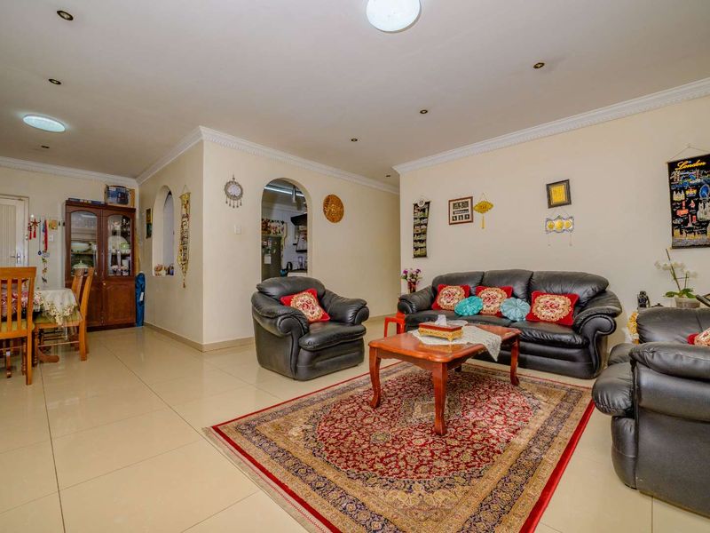 Spacious open-plan living and dining area featuring neutral tiled flooring, decorative archways, and recessed ceiling lighting.