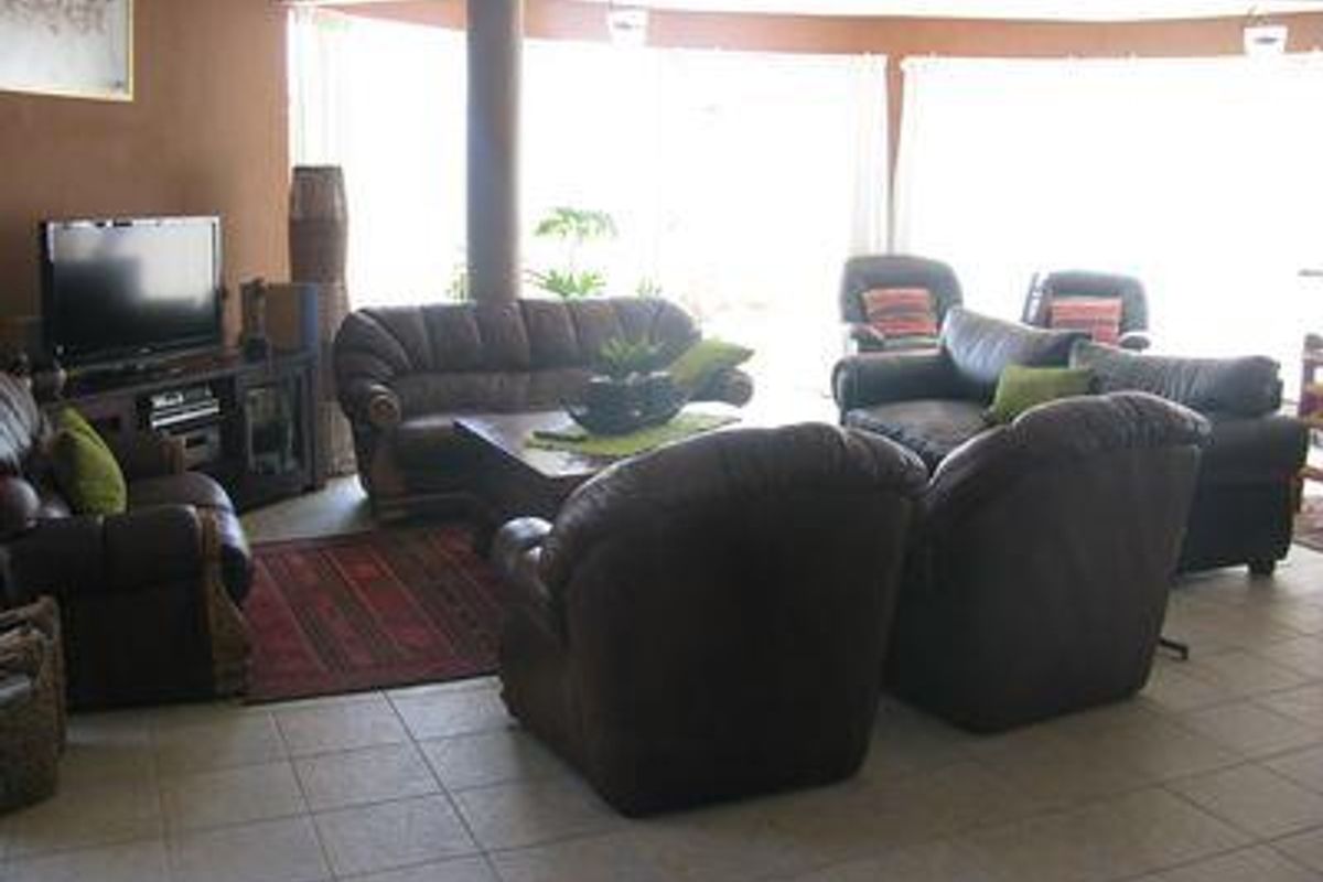 Spacious living room featuring tiled flooring, a central structural column, and large glass sliding doors providing ample natural light.