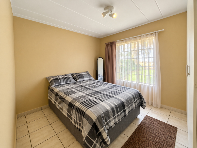 A functional bedroom featuring tiled flooring, a built-in wardrobe, and a window with natural light, providing a neutral base for personalization.