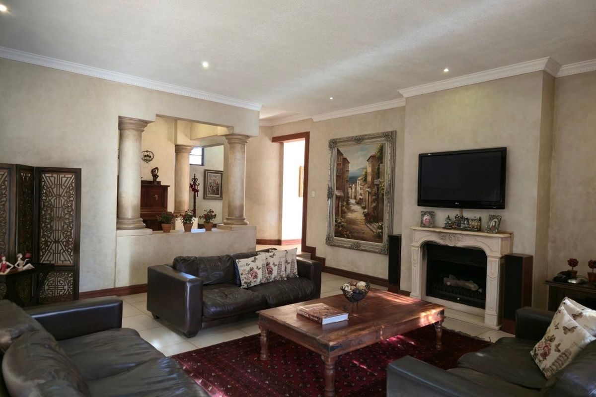 Spacious living room featuring a decorative fireplace, textured wall finishes, and architectural columns separating the adjacent space.