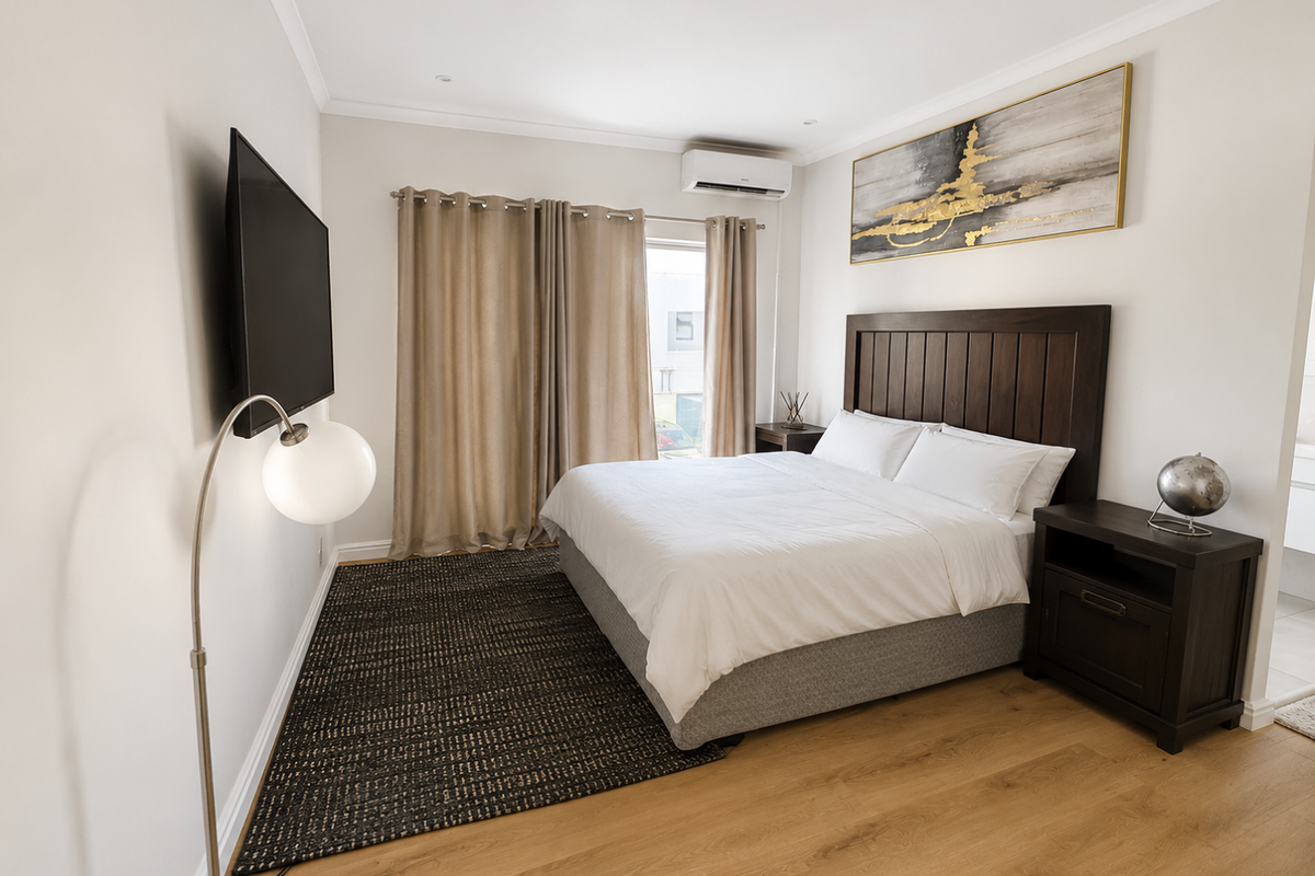 A well-maintained bedroom featuring light wood flooring, a wall-mounted air conditioning unit, and neutral wall finishes.