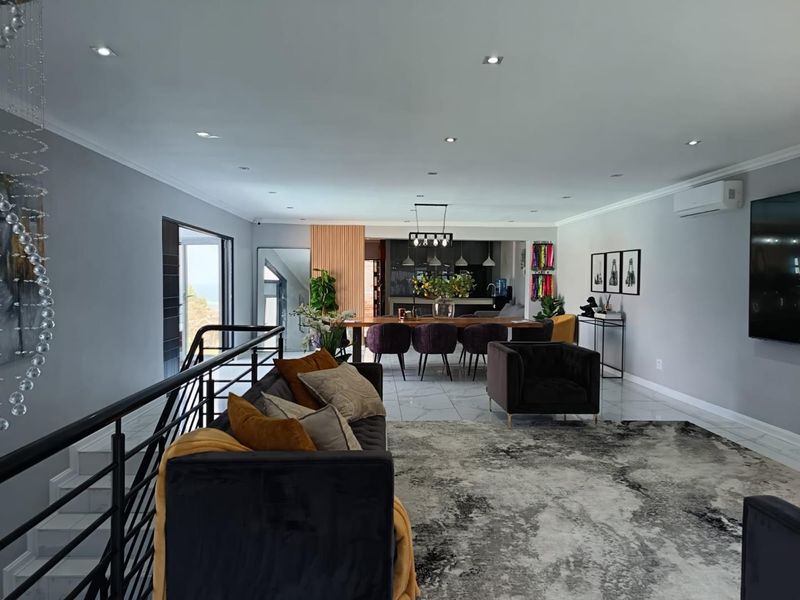 Spacious open-plan living and dining area featuring modern tiled floors, recessed lighting, a sleek feature wall, and integrated air conditioning.