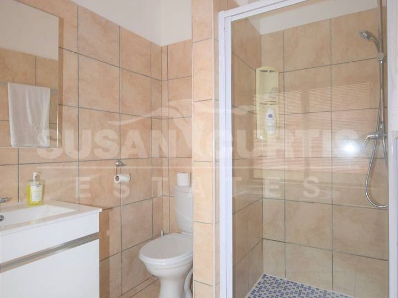 A functional bathroom featuring a glass-enclosed shower, wall-mounted vanity, and neutral ceramic tiling throughout.