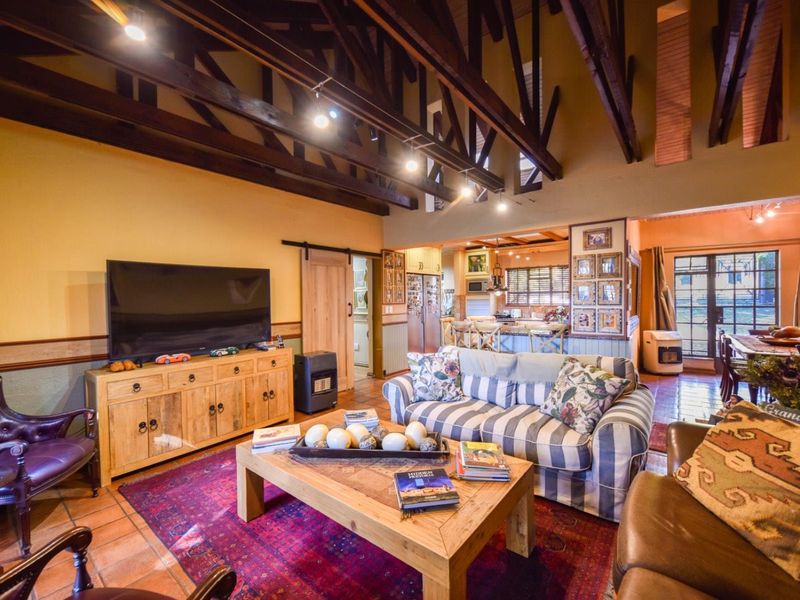 Spacious open-plan living area featuring high vaulted ceilings with exposed timber trusses, terracotta flooring, and a seamless flow into the adjacent kitchen space.