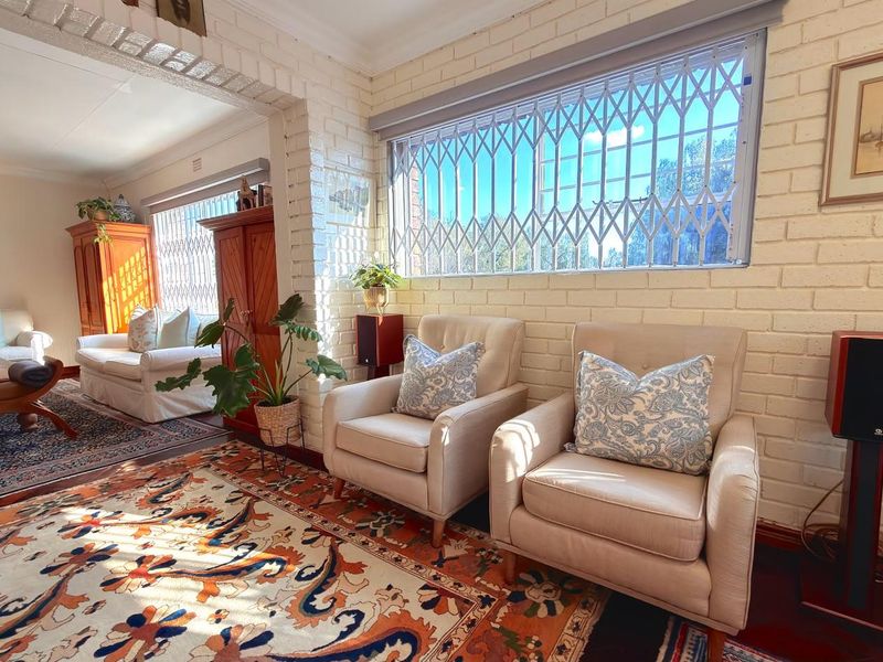 A bright living room featuring exposed white brick walls, timber flooring, and secure window treatments, creating a warm and inviting atmosphere.