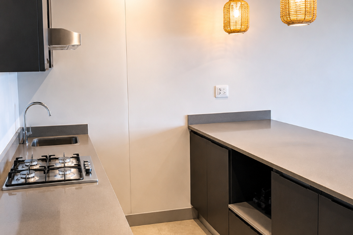 Modern kitchen featuring dark cabinetry, stone countertops, a gas hob, integrated extractor fan, and sleek tiled flooring in a clean, minimalist layout.