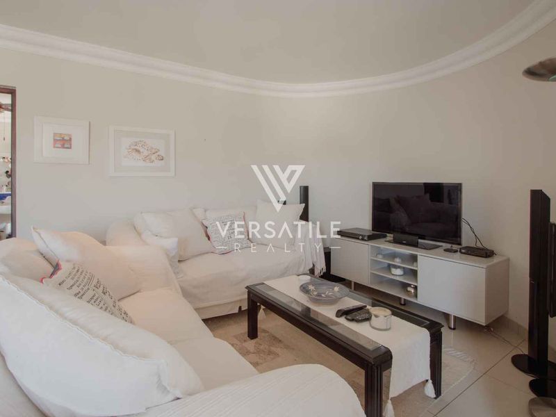 A comfortable living room featuring tiled flooring, coved ceiling detailing, and neutral wall finishes, providing a functional and inviting space.
