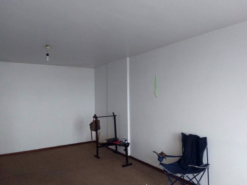 A spacious, empty living area featuring neutral walls and carpeted flooring, providing a blank canvas for personalization.