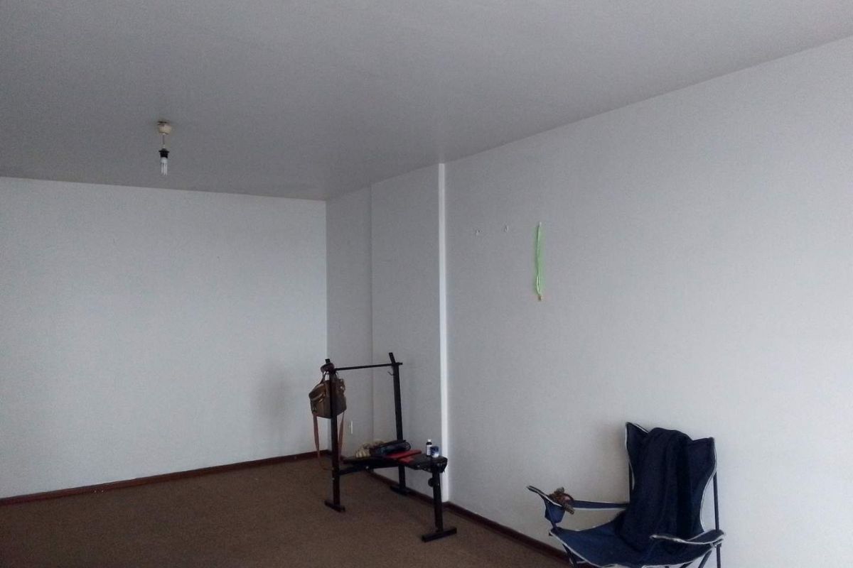 A spacious, empty living area featuring neutral walls and carpeted flooring, providing a blank canvas for personalization.
