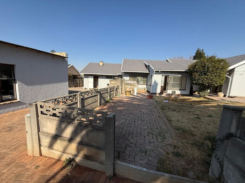 Rear view of the property featuring a paved courtyard area, precast concrete boundary walls, and a tiled roof structure.