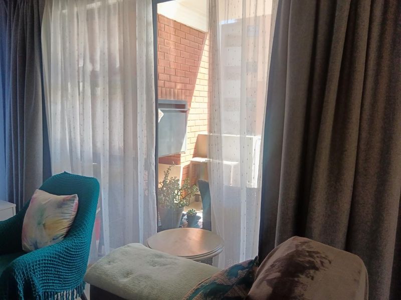 A living room area featuring a large sliding glass door that opens onto a private balcony with a brick wall finish.