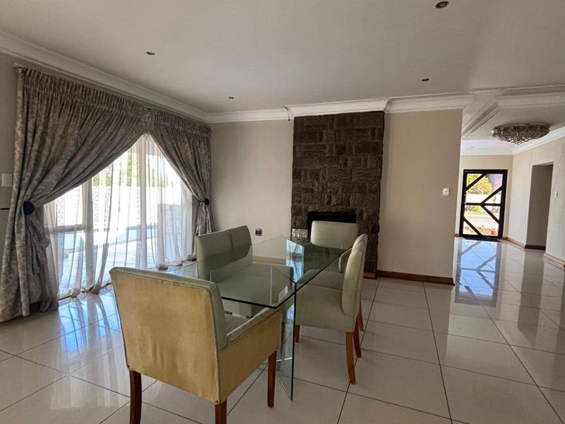 Spacious dining area featuring polished porcelain floor tiles, a prominent stone fireplace, and large sliding glass doors providing natural light and access to the exterior.