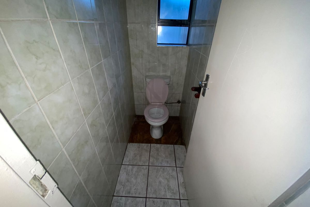 A small, functional guest toilet featuring full-height wall tiling and a tiled floor, providing a basic and compact utility space.
