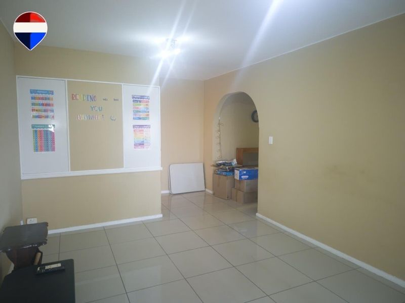 A spacious living area featuring neutral tiled flooring and an arched entryway, providing a versatile blank canvas for interior design.