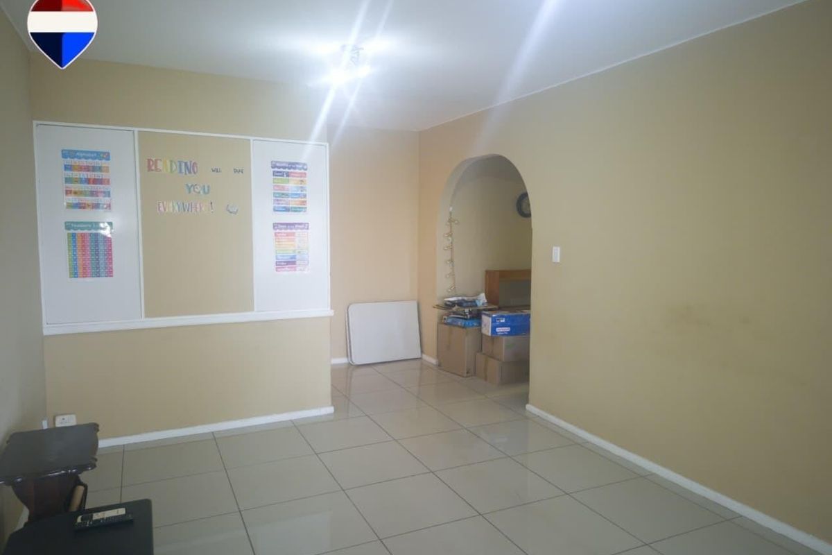 A spacious living area featuring neutral tiled flooring and an arched entryway, providing a versatile blank canvas for interior design.