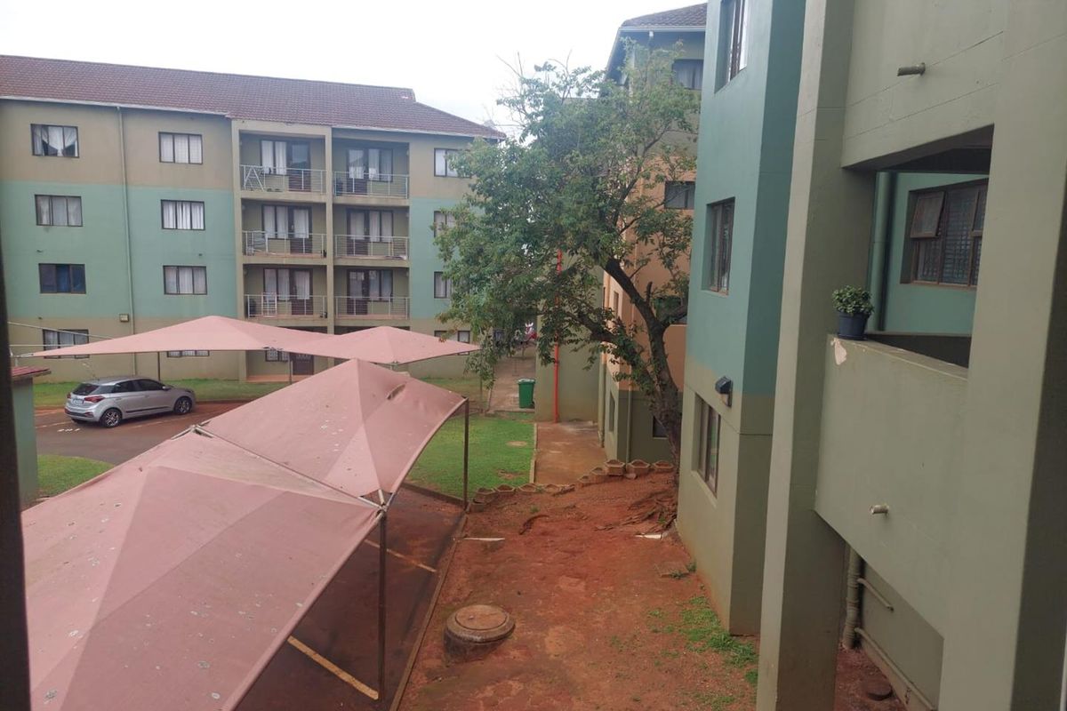 View of the apartment complex exterior featuring multi-story residential blocks, shade cloth carports, and communal outdoor areas.