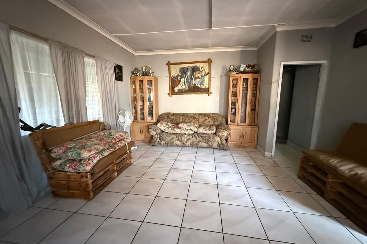 A living room featuring neutral tiled flooring, coved ceilings, and built-in wooden display cabinetry.