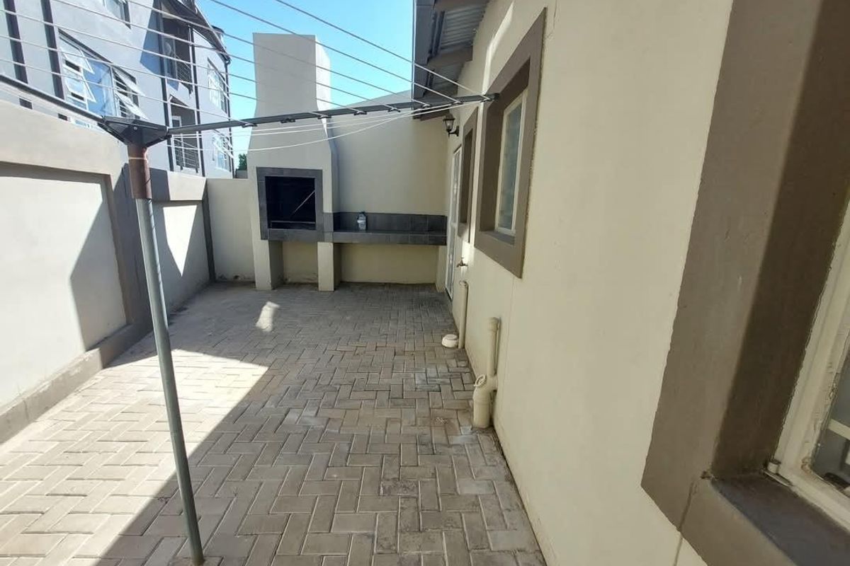 A paved rear courtyard featuring a built-in brick braai and a fixed washing line, providing a functional outdoor space for the townhouse.