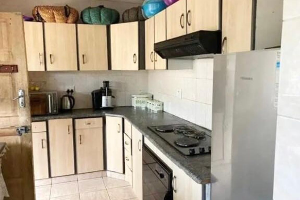 A functional kitchen featuring laminate cabinetry, a built-in hob, an extractor fan, and tiled flooring with a tiled backsplash.