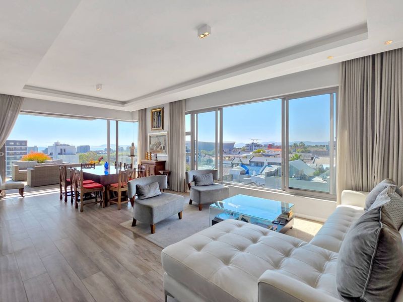 Spacious open-plan living and dining area featuring floor-to-ceiling sliding glass doors with expansive city and coastal views.
