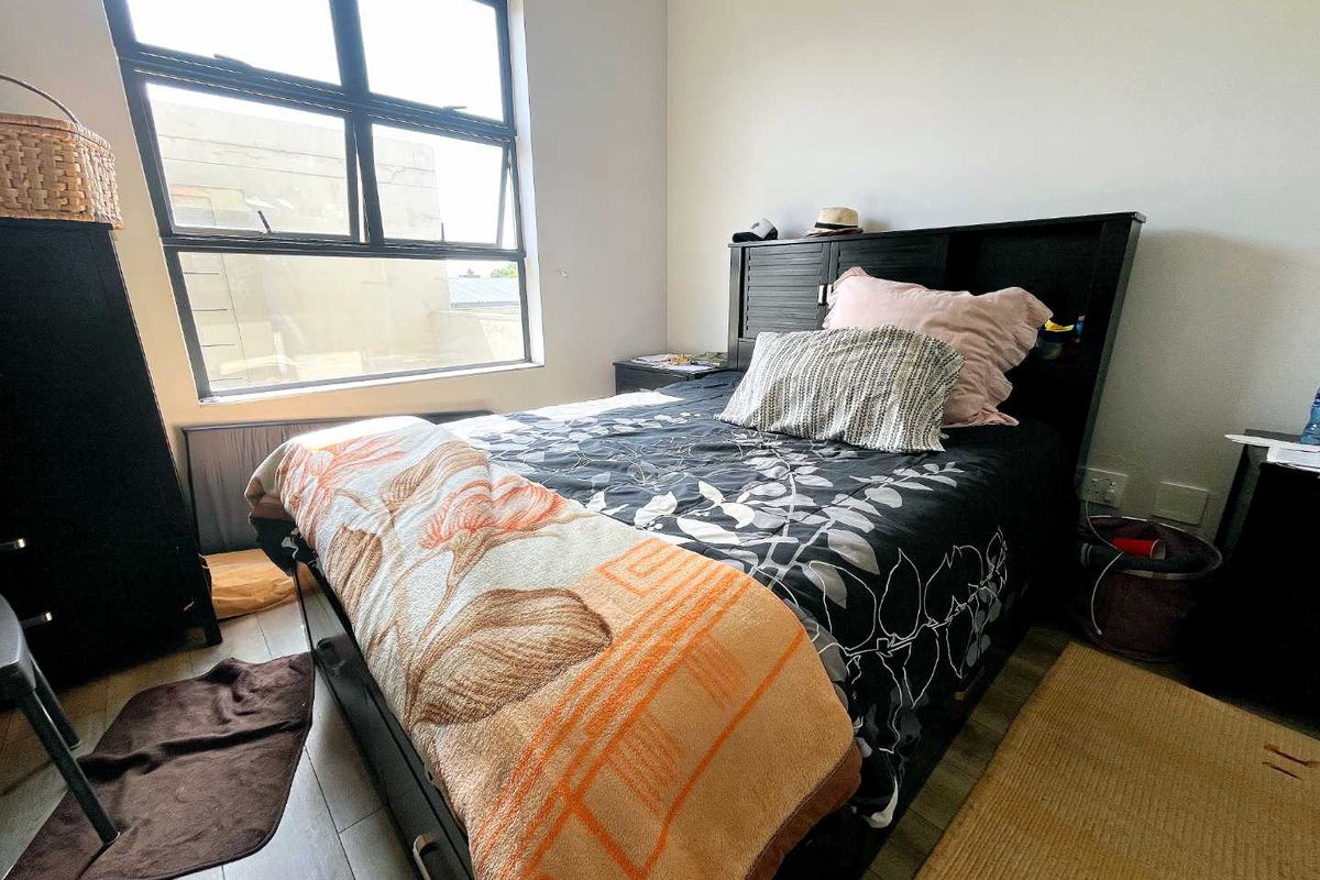 A bedroom featuring large aluminum-framed windows that provide natural light and modern wood-look flooring.