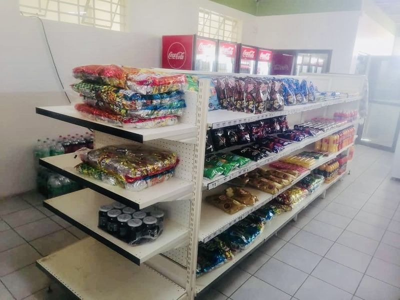 Interior view of a retail space featuring commercial display shelving units and integrated refrigeration units with tiled flooring.