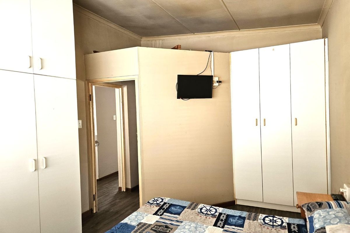 Bedroom featuring built-in white cabinetry and a doorway leading to an adjacent hallway.