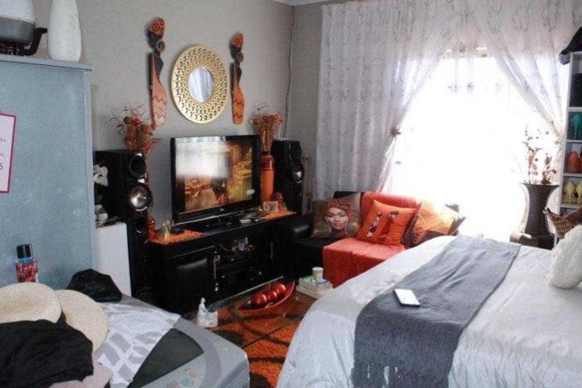 A bedroom featuring a large window with sheer curtains, providing natural light to the space.