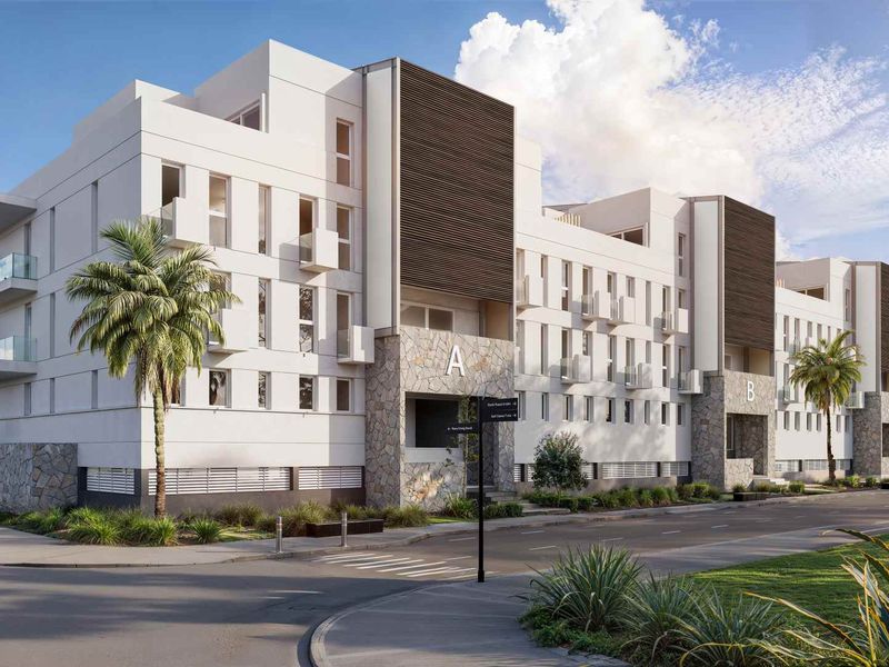 A modern apartment complex featuring contemporary architectural design with stone cladding, glass balconies, and landscaped surroundings.