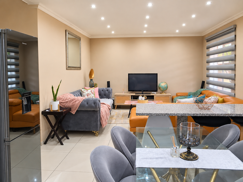 A well-maintained open-plan living and dining area featuring tiled flooring, recessed downlighting, and a granite breakfast bar.