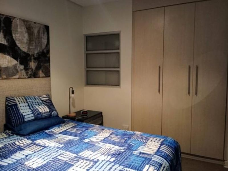A bedroom featuring a built-in wardrobe with light wood-finish doors and a louver-style window providing natural light.
