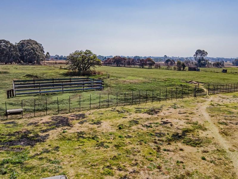 Aerial view of the small holding property featuring expansive open pasture land, perimeter fencing, and a dedicated livestock enclosure.