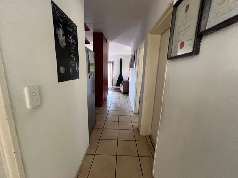 A tiled hallway leading from the entrance area towards the living space, featuring a visible freestanding fireplace in the distance.