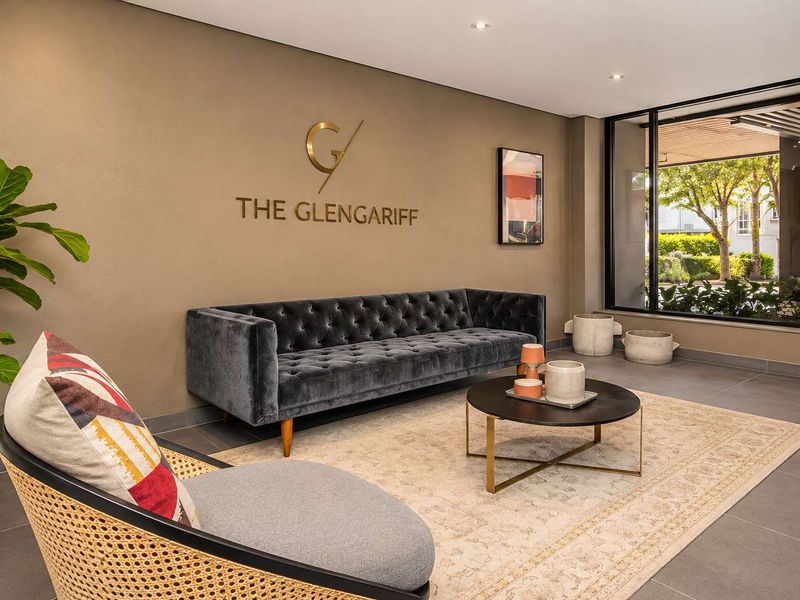 A modern and well-maintained apartment building entrance lobby featuring large format floor tiles, recessed lighting, and a feature wall with building signage.