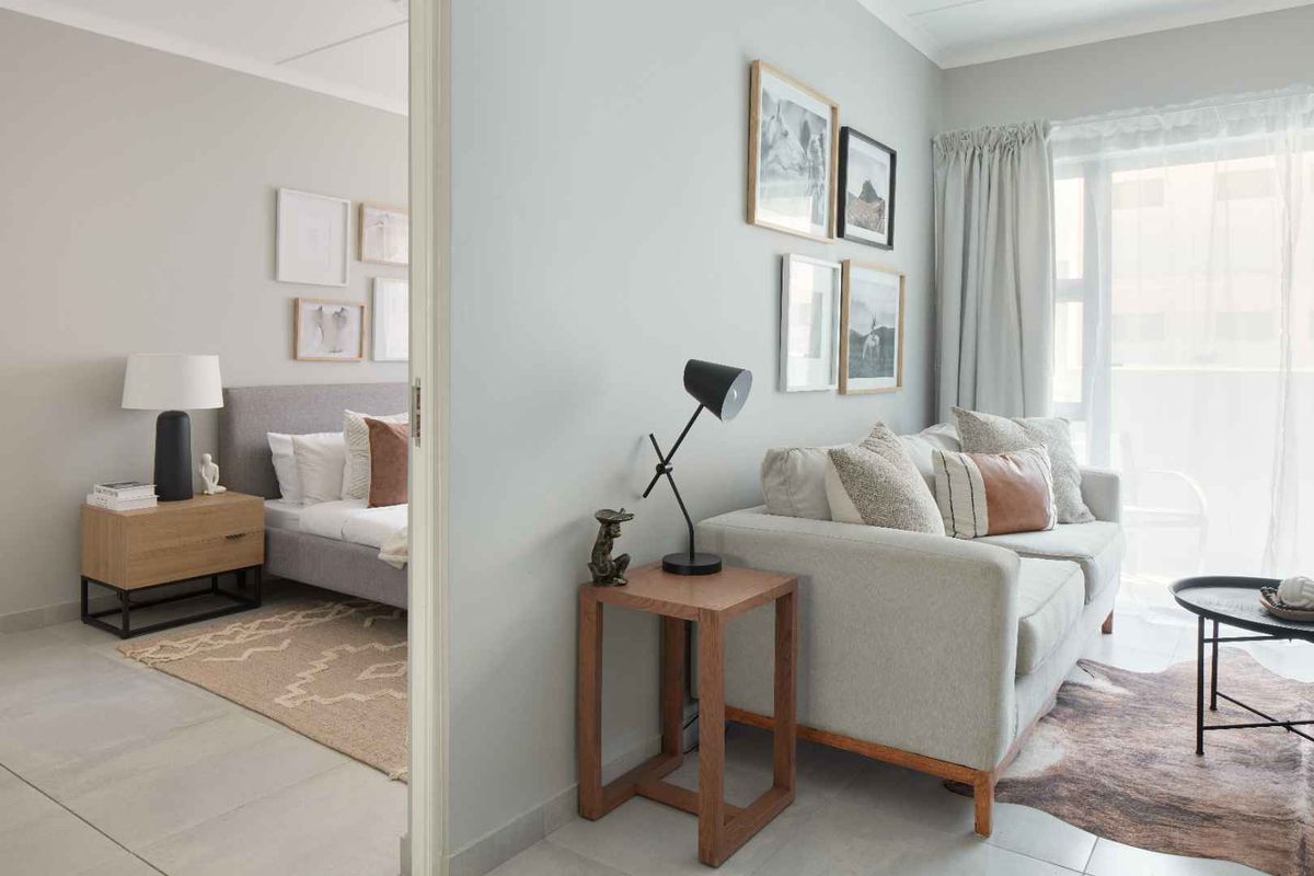 A bright and modern living area featuring neutral tones, tiled flooring, and direct access to an outdoor space through a sliding glass door.