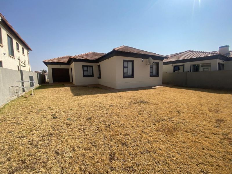 Rear view of the house featuring a tiled roof, neutral exterior walls, and a private backyard with boundary walling.