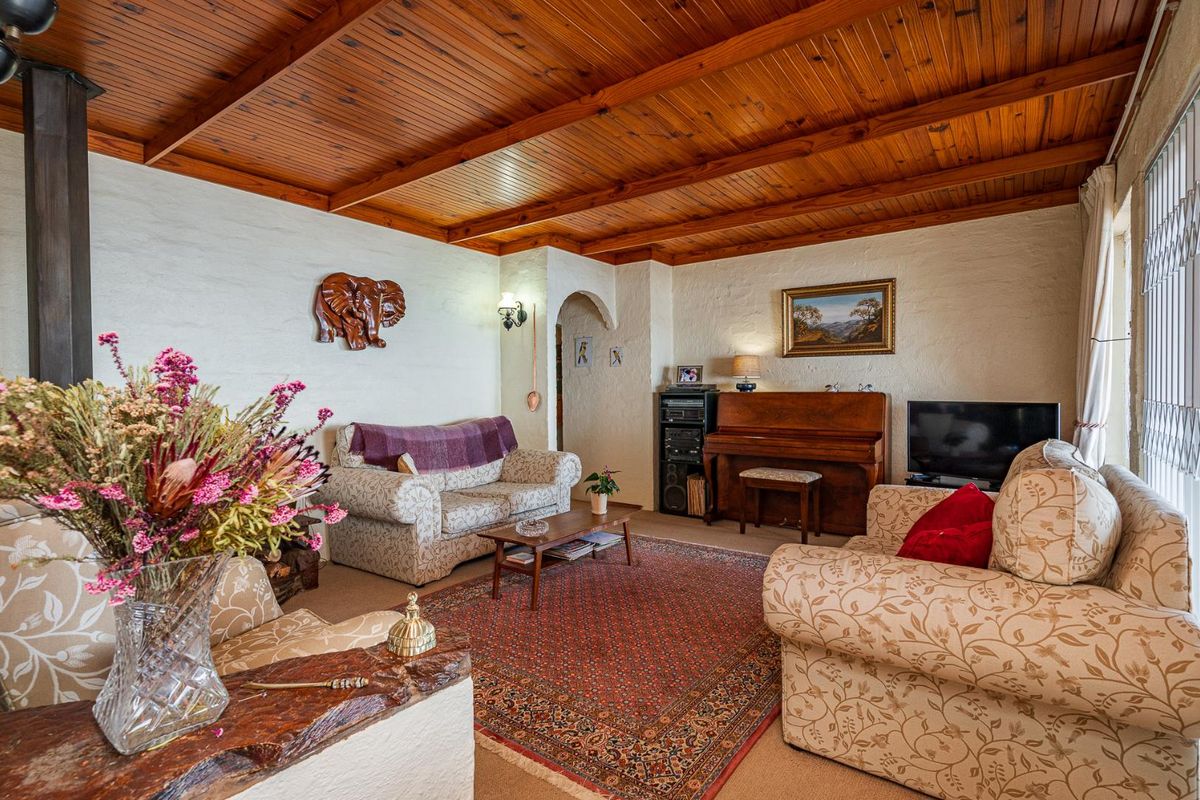 A cozy living room featuring a warm timber-clad ceiling with exposed beams, textured walls, and a classic archway leading to adjacent spaces.