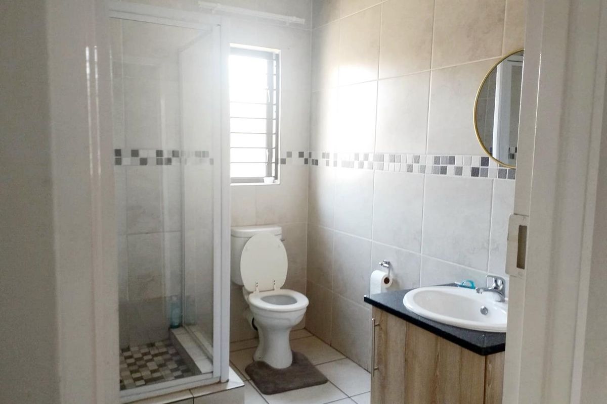 A functional bathroom featuring a glass-enclosed shower, a toilet, and a vanity cabinet with a basin and granite countertop.