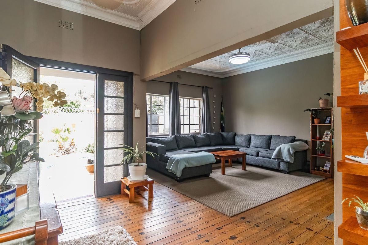 Spacious living room featuring original pressed metal ceilings, polished timber flooring, and direct access to an outdoor patio area.