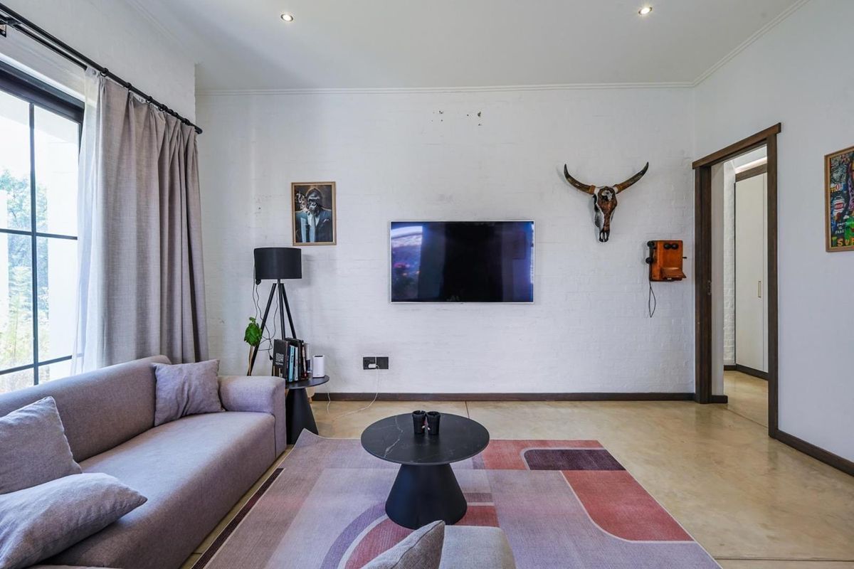 A bright living room featuring polished concrete floors, an exposed white brick feature wall, and recessed downlighting, creating a modern industrial aesthetic.