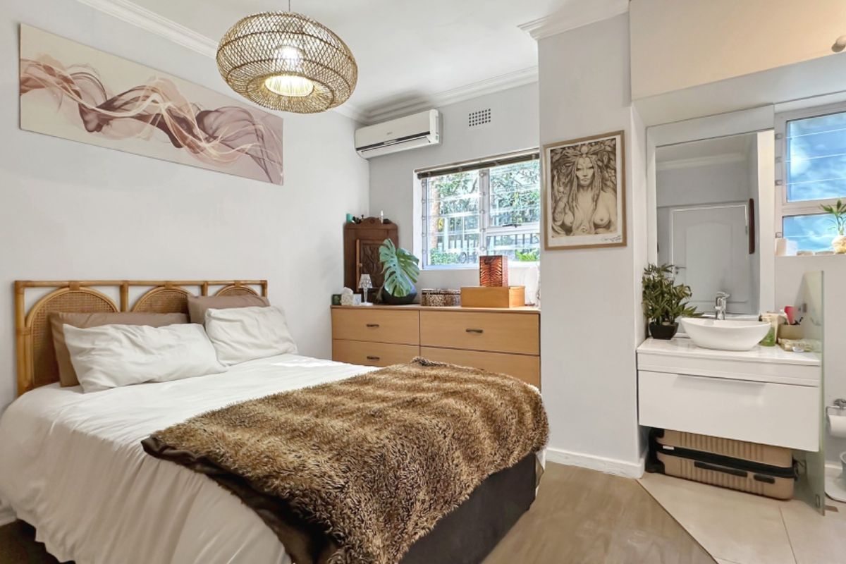 A well-maintained bedroom featuring a built-in vanity with a vessel sink, split-system air conditioning, and crown molding details.
