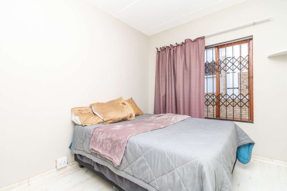 A bedroom featuring a window with security bars and neutral wall finishes.